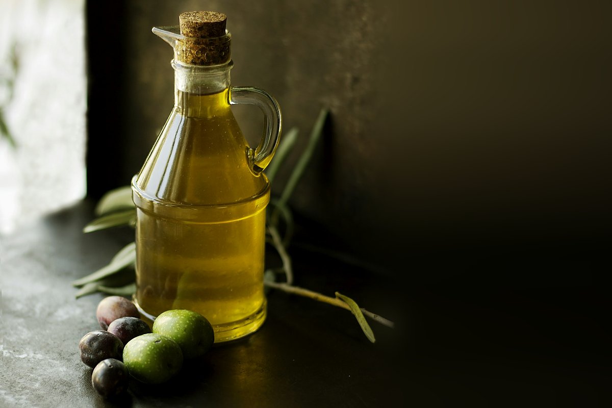 Bottle of olive oil with olives on a dark background
